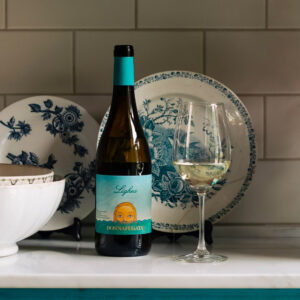 Donnafugata Lighea Sicilia DOC Zibibbo ha un colore giallo paglierino brillante, con lievi riflessi verdolini. Al naso offre un bouquet ricco e fragrante, dove, alle classiche note di zagara, si uniscono sentori agrumati di cedro e bergamotto e frutta esotica come come il litchi. Al palato risulta di beva estremamente scorrevole, nel quale ritornano le note floreali e fruttate, accompagnate da una spiccata freschezza. Chiude con un finale piacevolmente persistente, con un'interessante vena minerale. Lighea è un classico di Donnafugata, un bianco prodotto dal 1990, apprezzato in tutto il mondo per la sua grande espressività. La sua fresca aromaticità esprime con semplicità e leggerezza i sapori e i profumi dell'isola di Pantelleria, dove nasce il nobile Zibibbo, chiamato anche Moscato d'Alessandria.Fa parte della collezione “Versatili e di Carattere” di Donnafugata, vini piacevoli dall’animo siciliano. Da bere quando lo si desidera, rappresenta un piccolo “lusso quotidiano”. “Dai disordinati capelli color di sole l’acqua del mare colava sugli occhi verdi apertissimi”... così Giuseppe Tomasi di Lampedusa descrive Lighea, l’ammaliante sirena personaggio centrale di un suo racconto che ha dato spunto ad un vino complesso ed innovativo e ad una etichetta altrettanto originale. “Non è stato facile - racconta Gabriella, fondatrice di Donnafugata insieme al marito Giacomo - stampare quest’etichetta e conservare le mille sfumature dei colori dell’isola, ritratti nel bozzetto originale”. Con l'annata 2023, Donnafugata riconferma il suo impegno per la sostenibilità adottando la bottiglia Cento per Cento Sicilia e il tappo Nomacorc Ocean, ottenuto da plastiche riciclate raccolte nelle zone costiere. La bottiglia borgognotta ha il vantaggio di essere più leggera (410g) ed è prodotta in Sicilia con vetro riciclato, secondo il modello di economia circolare promosso dalla Fondazione SOStain e messo in pratica dalla vetreria O-I Glass. L'etichetta di Lighea è stata inoltre oggetto di restyling: le sfumature del tramonto hanno lasciato spazio a quelle dell'alba pantesca, esprimendo la personalità di questo vino grazie allo sguardo ammaliante della sirena. 