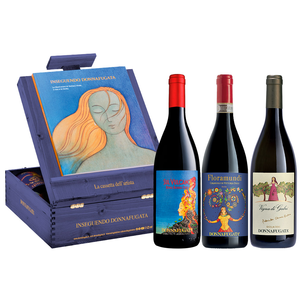 Confezione regalo "Inseguendo Donnafugata", realizzata in legno blu e contenente 3 etichette Donnafugata rappresentative della Sicilia. La "cassetta dell'artista" rende omaggio al legame indissolubile tra Donnafugata e l'Arte: una cassetta in legno multiuso, che si trasforma in cavalletto da tavolo e scatola dei colori. Contiene inoltre il catalogo "Inseguendo Donnafugata", con le illustrazioni del designer Stefano Vitale, con cui Donnafugata collabora da decenni. Elegante e preziosa cassetta, il regalo perfetto per gli appassionati del vino e del buon gusto. La cassetta contiene: 1x Vigna di Gabri Sicilia DOC 0,75L - Vino Bianco, 1x Floramundi Cerasuolo di Vittoria DOCG 0,75L - Vino Rosso, 1x Sul Vulcano Etna Rosso DOC 0,75L - Vino Rosso