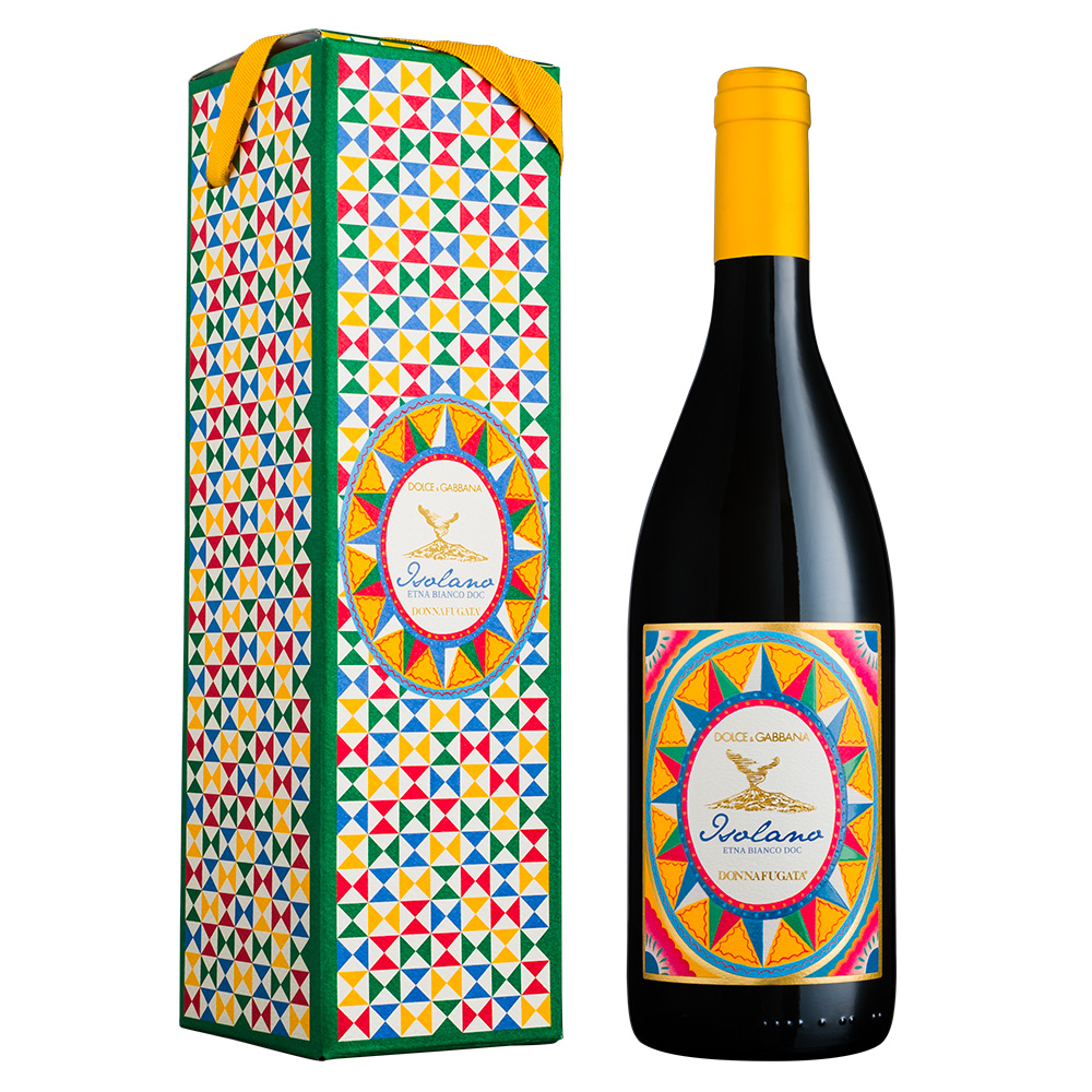 Isolano è il nuovo vino bianco dell'Etna che nasce dalla collaborazione tra Donnafugata e Dolce&Gabbana, entrambi ambasciatori d'eccellenza della cultura siciliana e del Made in Italy. Ha così origine un'etichetta prestigiosa, un bianco avvolgente, elegante e straordinariamente minerale, frutto della viticoltura di montagna alle pendici dell'Etna, che esprime il calore mediterraneo delle terre siciliane e i valori di creatività e artigianalità. Donnafugata Isolano Limited Edition Dolce&Gabbana Etna Bianco DOC ha un colore giallo paglierino brillante. Al naso spicca un raffinato bouquet con fragranti sentori agrumati di scorza di limone, note fruttate di mela gialla ed infine erbe aromatiche mediterranee. Isolano è un vino di avvolgente eleganza, che si distingue al palato per la persistenza e la straordinaria mineralità vulcanica. Dolce&Gabbana ha curato l'immagine di questo vino rivoluzionario, esaltando i colori della Sicilia sia nella grafica dell'etichetta e dell'astuccio, ma anche nella scelta cromatica della capsula e del nastro in gros-grain. I motivi e le forme geometriche sono quelle tipiche del carretto siciliano, in cui dominano il rosso, il verde, il blu e il giallo. Un vino da godere subito o da collezionare: se ben conservato, la sua longevità va oltre i 10 anni.