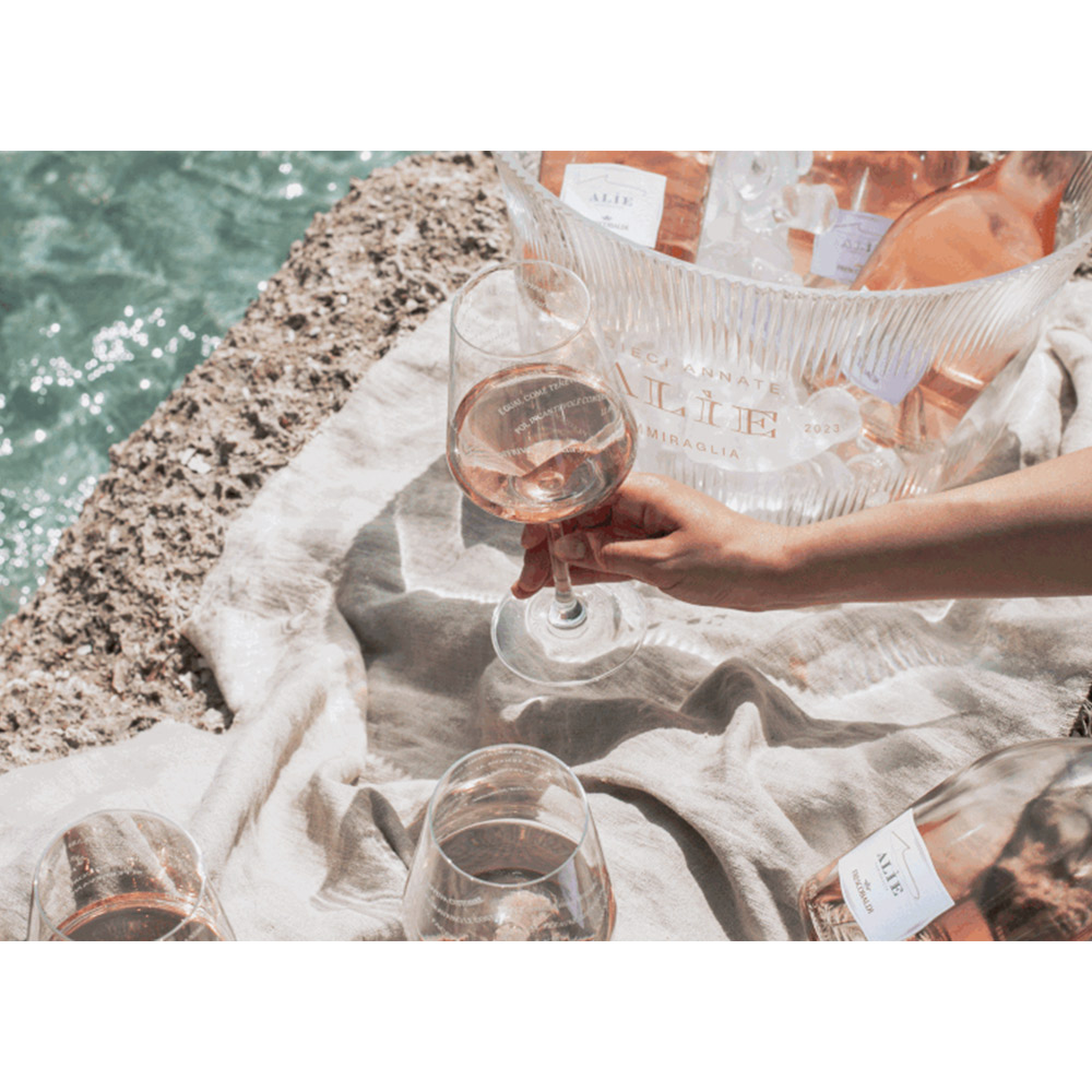 Frescobaldi Alìe Rosé 2023 - Promozione speciale: Box 6 Bottiglie + 6 Calici + 6 Sottobicchieri Limited Edition - Alìe 2023: un'edizione speciale dedicata all'iconico rosé di Tenuta Ammiraglia. Alìe celebra la sua decima vendemmia e, per l'occasione, abbiamo pensato ad un'offerta speciale con calici e sottobicchieri in edizione limitata ed ispirata al mito di Alìe, la ninfa della mitologia greca simbolo di sensualità ed eleganza, da cui il vino prende il nome. Il mito di Alìe viene rievocato nel poema epico a lei dedicato: Alìade. Alìe, ninfa del mare, animo gentile, Alìe la sua isola doveva custodire. E guai, come teneva al suo mare. Quando i marinai sfioravano le coste, lei li osservava navigare. Poi, incantevole com'era, li accompagnava per un tratto.Faceva loro compagnia, regalava una risata. Al termine del viaggio offriva un elisir sublime. E mentre loro si perdevano nel rosa, lei nella sua isola tornava. - Frescobaldi Alìe Rosé Toscana IGT ha un colore rosa tenue, vivace e luminoso. Al naso spiccano sentori fruttati piuttosto intensi, tra cui quelli di pesca nettarina, ma anche ricordi floreali di rosa e peonia. Le note agrumate, perfettamente integrate al contesto, donano una meravigliosa freschezza, ancor più accentuata dai delicati sentori iodati. Il bouquet è tutto in divenire ed, in un secondo momento, compaiono sensazioni di erbe aromatiche come timo e salvia. Al palato si percepisce la delicatezza di questo rosé, grazie anche alla corrispondenza gusto olfattiva impressionante e alla mineralità. È nitido, fresco e leggero, particolarmente equilibrato ed armonico. Colpisce per la grande agilità di beva, nonché per il suo carattere "sensuale". Alìe è il nome di una delle ninfe marine greche, da sempre simbolo di sensualità e bellezza. Le stesse caratteristiche si adeguano perfettamente a questo rosé, ottenuto da un blend Syrah e Vermentino, coniugati perfettamente in un risultato raffinato ed espressivo. Le uve Syrah gli conferiscono un colore rosato attraente e delicato, senza il bisogno della macerazione, mentre il Vermentino contribuisce a donare, in maniera impeccabile, quell'equilibrio fresco-sapido caratteristico di questa etichetta.