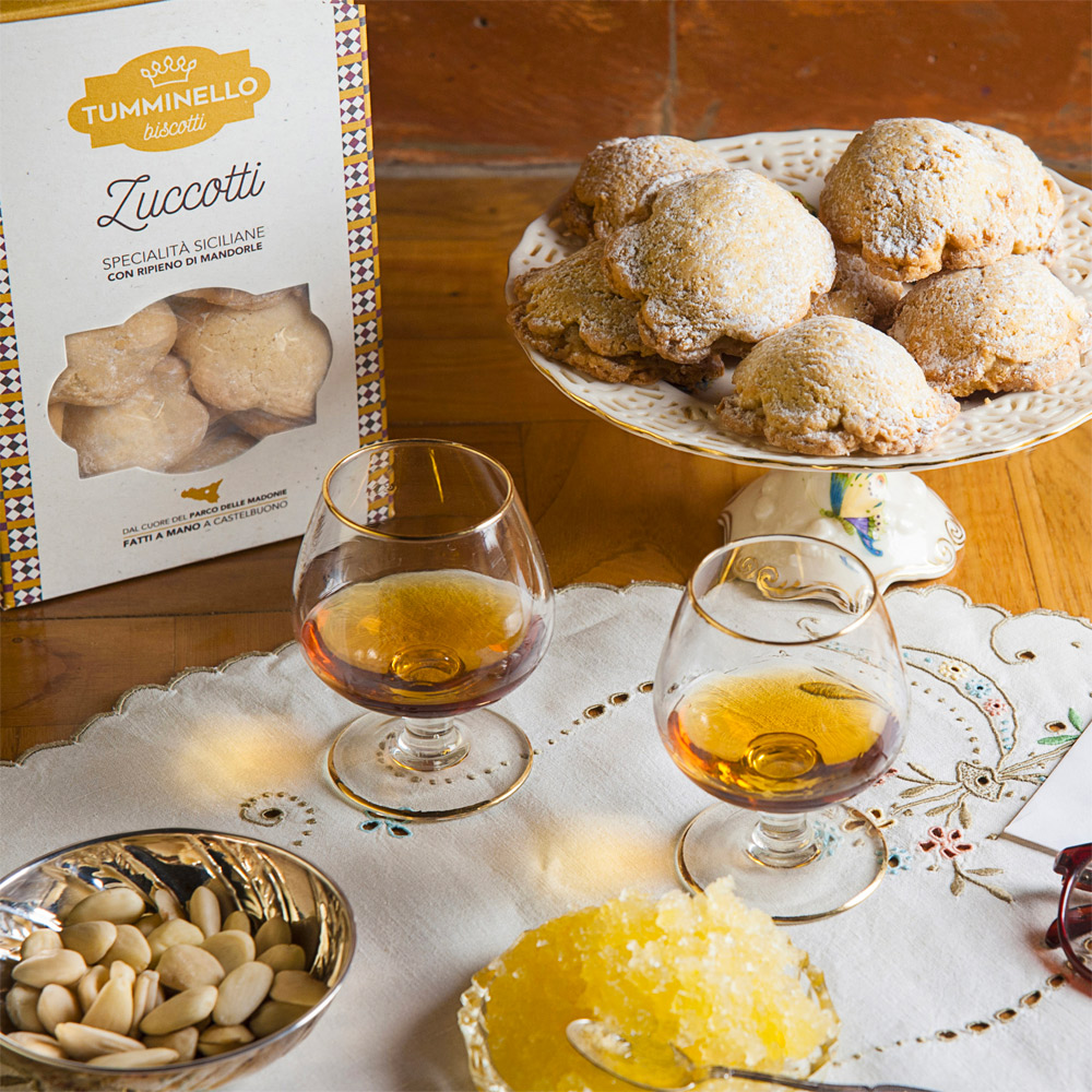 Tumminello Biscotti Zuccotti Specialità Siciliane ripiene di Mandorle 320g - Gli Zuccotti, dolci tipici della tradizione natalizia di Castelbuono, sono un delicato piacere che oggi è possibile gustare tutto l’anno.Con uno squisito ripieno di zuccata, mandorle e cannella, assicurano un sapore sfizioso che richiama alla mente i sapori ed i profumi dell’autentica tradizione dolciaria siciliana.Il delizioso involucro di pasta frolla ed il goloso ripieno sprigionano sapori unici ai quali è impossibile resistere. Questi dolci panciuti, ricoperti di glassa e confettini di zucchero, possono essere gustati tutto l’anno a fine pasto come sfizioso dessert, nel pomeriggio accompagnato da un tè o semplicemente come goloso intermezzo durante la giornata.