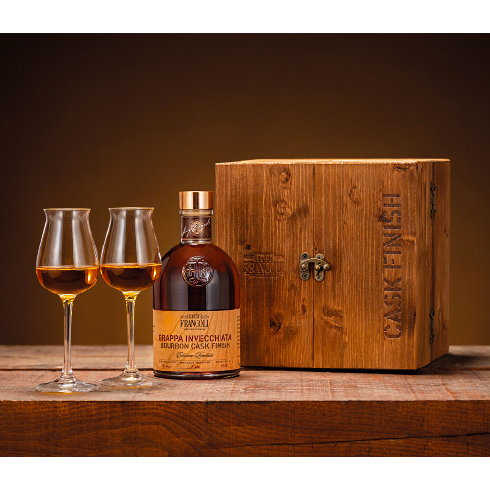 Francoli Cask Finish Bar: un elegante mobiletto bar realizzato in legno racchiude due bicchieri da degustazione, una bottiglia di grappa invecchiata Luigi Francoli Bourbon Cask Finish e una tavoletta di Cioccolato di Modica IGP alla Vaniglia Bourbon.  La grappa ha soggiornato in botti utilizzate in precedenza per affinare il Bourbon ed è prodotta in edizione limitata di circa 3000 bottiglie. Questa magnifica confezione regalo è l'occasione perfetta per trascorrere momenti estremamente piacevoli e conviviali.  - Luigi Francoli Grappa Bourbon Cask Finish Di un bel colore ambrato, connotato da riflessi ramati. Al naso emerge un bouquet sfaccettato che ricorda la nocciola e la mandorla tostata, seguiti da fiori secchi e spezie. Al palato è perfettamente equilibrata, sontuosa e ampia, caratterizzata da un gusto in cui i sentori di legno e vaniglia fanno da padroni.