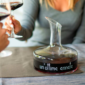 Decanter vino in vetro Un'Ottima Annata Simple Day - Il decanter è uno strumento fondamentale per valorizzare un vino rosso ed ha, senza dubbio, un effetto scenografico sulla tavola. Questo oggetto è stato reinterpretato, modernizzando la forma e applicando una scritta che lo rende ancora più particolare. Questo oggetto è anche un ottima idea regalo adatta anche per un pubblico sia femminile che maschile, soprattutto se wine lovers o appassionati. Decanter per bottiglie di vino da 0,75L, Altezza 21 cm x ø 19 cm, Decoro Un'Ottima Annata serigrafato in colore bianco, Lavare a mano. Non utilizzare detersivi abrasivi o aggressivi. Vetro cristallino senza piombo, soffiato a bocca. Eventuali piccole bolle d'aria nel vetro sono caratteristiche di questo tipo di lavorazione. Confezione in cartone riciclato, Disegnato in Italia