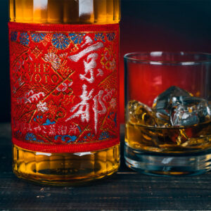 Aka-Obi Red Belt, prodotto dalla Kyoto Miyako Distillery, è un whisky giapponese blended malt & grain, realizzato con cereali 100% giapponesi nel rispetto della tradizione nipponica. Si distingue per il carattere fruttato e l’immediata piacevolezza. Alla vista si presenta con un colore ambrato chiaro e luminoso. Al naso sprigiona sentori dolci di vaniglia, mallo di noce, frutta secca e cereali. Al palato il malto emerge con eleganza, mentre le note morbide dei grain whisky rilasciano sfumature vanigliate. Affinato in botti di Virgin American Oak, questo whisky unisce raffinatezza e armonia. La sua etichetta, in pregiato tessuto giapponese ricamato, riflette l’artigianalità e l’eleganza della cultura giapponese.