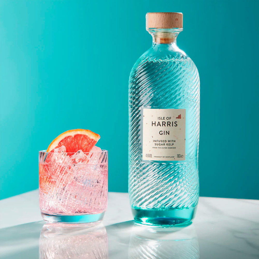 Isle of Harris Gin nasce sull’omonima isola al largo delle coste nord-occidentali della Scozia, nelle selvagge Ebridi Esterne. È un gin artigianale che incarna il carattere marino e autentico del territorio da cui proviene: ventoso, puro, essenziale. Il suo profilo racconta il respiro dell’oceano e i paesaggi incontaminati dell’isola, grazie a una botanica distintiva, l’alga Sugar Kelp, raccolta nei fondali marini locali. Il progetto nasce dal desiderio di Anderson Bakewell di catturare la bellezza e le atmosfere uniche dell’isola in un distillato. La distilleria è stata fondata nel 2015 nel villaggio costiero di Tarbert, e la produzione avviene in piccoli lotti, con un alambicco in rame e acqua purissima proveniente dalla sorgente di Abhainn Cnoc. La ricetta prevede nove botaniche, scelte con cura per esprimere freschezza, eleganza e territorialità: ginepro, scorze di agrumi, erbe, spezie e, soprattutto, Sugar Kelp, che dona al gin una caratteristica nota iodata e salina. Alla vista è cristallino e limpido. Al naso colpisce per la sua eleganza aromatica: note balsamiche di ginepro, aghi di pino, scorza di lime e pompelmo, erbe officinali, pepe bianco e una netta impronta marina. Al palato è armonico e setoso, con una piacevole freschezza salina che accompagna un finale lungo, pulito e balsamico. La bottiglia è un capolavoro di design firmato dallo studio Stranger & Stranger: vetro lavorato con onde in rilievo che evocano il mare, tappo in sughero naturale e un’etichetta minimale, a sottolineare l’eleganza sobria del progetto.
