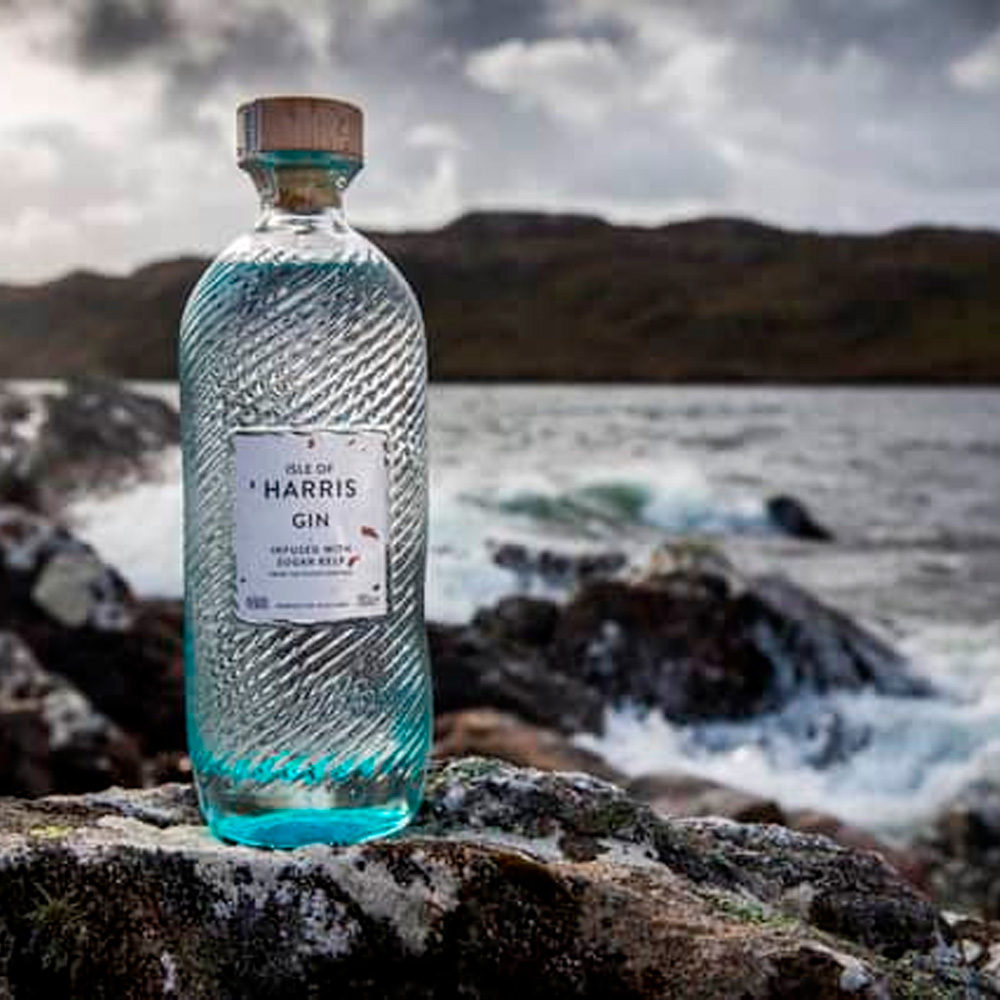 Isle of Harris Gin nasce sull’omonima isola al largo delle coste nord-occidentali della Scozia, nelle selvagge Ebridi Esterne. È un gin artigianale che incarna il carattere marino e autentico del territorio da cui proviene: ventoso, puro, essenziale. Il suo profilo racconta il respiro dell’oceano e i paesaggi incontaminati dell’isola, grazie a una botanica distintiva, l’alga Sugar Kelp, raccolta nei fondali marini locali. Il progetto nasce dal desiderio di Anderson Bakewell di catturare la bellezza e le atmosfere uniche dell’isola in un distillato. La distilleria è stata fondata nel 2015 nel villaggio costiero di Tarbert, e la produzione avviene in piccoli lotti, con un alambicco in rame e acqua purissima proveniente dalla sorgente di Abhainn Cnoc. La ricetta prevede nove botaniche, scelte con cura per esprimere freschezza, eleganza e territorialità: ginepro, scorze di agrumi, erbe, spezie e, soprattutto, Sugar Kelp, che dona al gin una caratteristica nota iodata e salina. Alla vista è cristallino e limpido. Al naso colpisce per la sua eleganza aromatica: note balsamiche di ginepro, aghi di pino, scorza di lime e pompelmo, erbe officinali, pepe bianco e una netta impronta marina. Al palato è armonico e setoso, con una piacevole freschezza salina che accompagna un finale lungo, pulito e balsamico. La bottiglia è un capolavoro di design firmato dallo studio Stranger & Stranger: vetro lavorato con onde in rilievo che evocano il mare, tappo in sughero naturale e un’etichetta minimale, a sottolineare l’eleganza sobria del progetto.