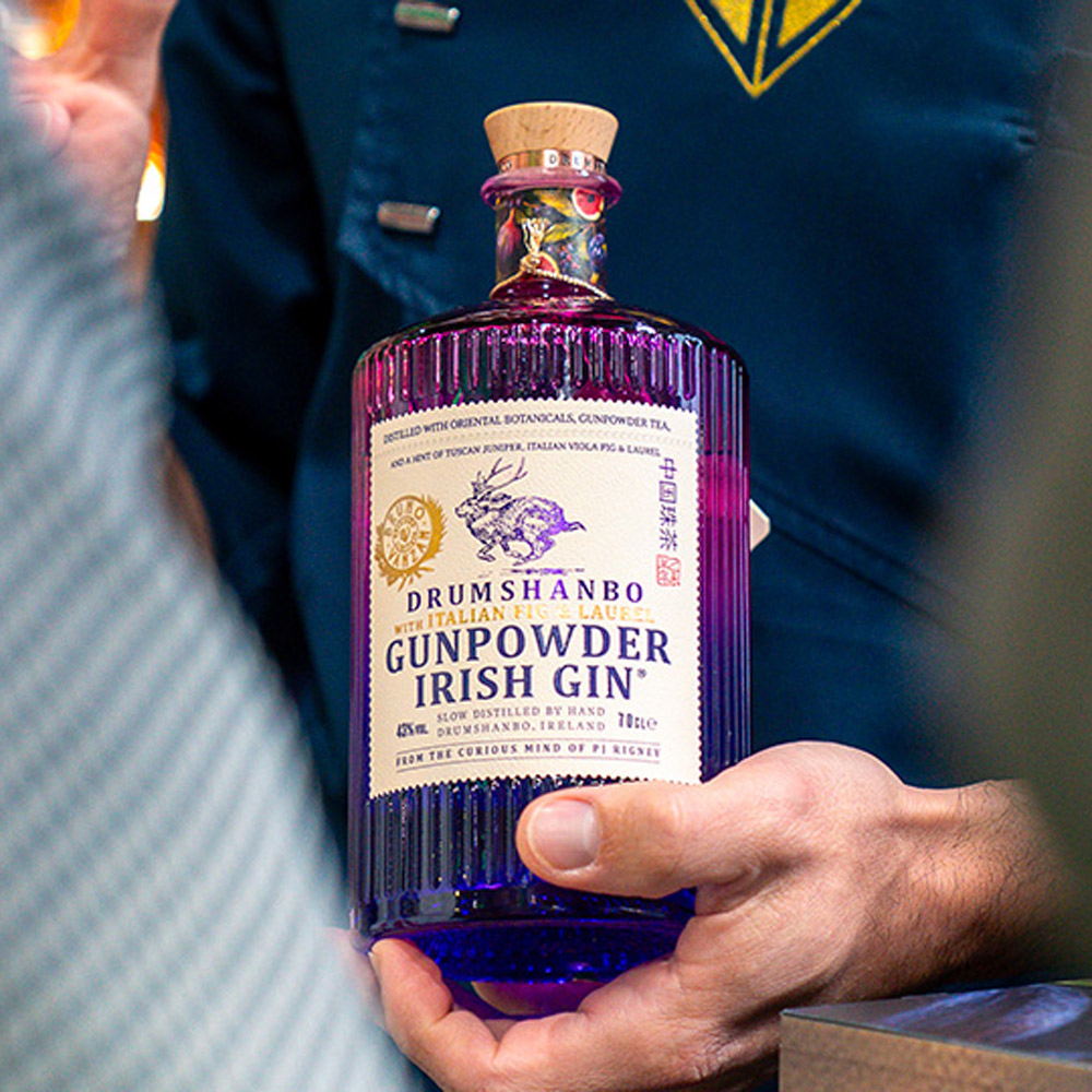 Drumshanbo Gunpowder Irish Gin Italian Fig & Laurel è un gin irlandese artigianale, distillato lentamente in tradizionali alambicchi di rame.Nasce dall’incontro tra la curiosità inesauribile del suo creatore, PJ Rigney, e la maestria artistica del bartender Bruno Vanzan, due esploratori uniti dal desiderio di fondere culture e sapori. Dalla loro collaborazione prende vita una creazione che unisce l’anima selvaggia dell’Irlanda all’eleganza mediterranea dell’Italia, grazie all’aggiunta di fico viola italiano, alloro e ginepro toscano alle botaniche tradizionali del Gunpowder. Rispetto alla versione classica, Italian Fig & Laurel mantiene il perfetto equilibrio tra le note speziate e agrumate tipiche della gamma, ma si distingue per la dolcezza vellutata del fico, la fresca aromaticità dell’alloro e la profondità balsamica del ginepro toscano. Il fico viola, frutto simbolo della tradizione mediterranea, apporta una naturale rotondità e un tocco soave al profilo aromatico, mentre l’alloro dona eleganza e una piacevole nota verde che richiama il profumo delle coste italiane. Alla vista si presenta limpido e cristallino. Al naso emergono sentori vegetali e fruttati, con note di tè, fico maturo e un accenno erbaceo di alloro. Al palato è fresco e rotondo, con un perfetto bilanciamento tra le note balsamiche di ginepro e quelle dolci e persistenti del fico, che accompagnano verso un finale lungo, morbido e raffinato. Il Gin Gunpowder nasce dall’estro di PJ Rigney, fondatore della Shed Distillery. Esploratore curioso e instancabile, PJ ha viaggiato per anni tra Cina, Cambogia, India, Macedonia, Marocco e Germania, fino a stabilirsi nella selvaggia e incontaminata Drumshanbo, nella contea di Leitrim, sulle rive del Lough Allen. È qui che ha dato vita alla sua distilleria, unendo botaniche orientali e irlandesi con metodi di distillazione tradizionali e artigianali.