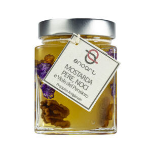 La Mostarda Pere, Noci e Viole del Pensiero è una variante innovativa, grazie al tocco distintivo delle viole del pensiero. Queste ultime conferiscono alla mostarda un tocco floreale intrigante e particolare, oltre che un tocco estetico di prestigio. Una composizione di sapori e consistenze unici: le pere mature sono dolci e succose, le noci donano croccantezza, il tutto completato dalle note floreali e colorate delle viole del pensiero. Si adatta particolarmente all'abbinamento con i formaggi stagionati o carni, ma è ottima anche gustata da sola. Grado di piccantezza generale: 9. Per le mostarde di frutta di Fredo vengono utilizzate solo le migliori materie prime di origine italiana.  Fredo vanta una lunga storia di produzione artigianale di mostarda e frutta candita, iniziata nel lontano 1890 a Brissago (Canton Ticino). Prodotta in esclusiva per EnoArt Enoteca da Fredo SA nel laboratorio di Cadenazzo (Svizzera). Prodotto artigianale, lavorato e confezionato a mano.Formato: Vasetto 400g