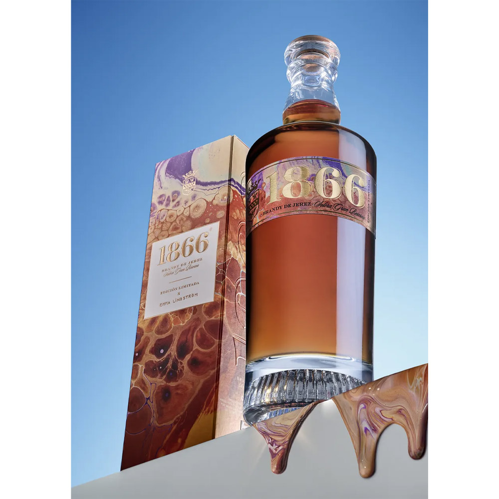 Osborne 1866 Brandy Solera Gran Reserva rappresenta l’eccellenza dell’arte distillatoria spagnola, un capolavoro nato da oltre 150 anni di tradizione e dal leggendario sistema “criaderas y solera” composto da 16 livelli di botti di rovere. Questa edizione limitata, creata in collaborazione con l’artista svedese Emma Lindström, unisce la maestria del blending di brandy e l’energia del colore fluido, celebrando l’armonia tra arte e tempo. Distillato da vini Airén della Mancia nelle tradizionali alquitaras di rame, il Brandy 1866 matura per una media di dodici anni in botti che hanno precedentemente contenuto i migliori sherry di Osborne. Il risultato è un brandy ricco, profondo e vellutato, dal colore mogano intenso con riflessi dorati, capace di conquistare gli appassionati più esigenti. Al naso rivela note di uvetta, vaniglia e caramello, mentre al palato esprime frutta secca, legni nobili e accenti salmastri che ne definiscono la morbidezza e la finezza. Il finale è lungo, caldo e rotondo, con una piacevole dolcezza bilanciata da tocchi secchi e speziati. Ogni bottiglia della Limited Edition 1866 x Emma Lindström è un’opera d’arte: i toni ambra, oro e terra evocano i colori del brandy e del paesaggio andaluso di El Puerto de Santa María, dove nasce e invecchia.Un brandy leggendario, simbolo di passione, equilibrio e tradizione, che racchiude nel suo profumo tutta la storia e l’anima dell’Andalusia.
