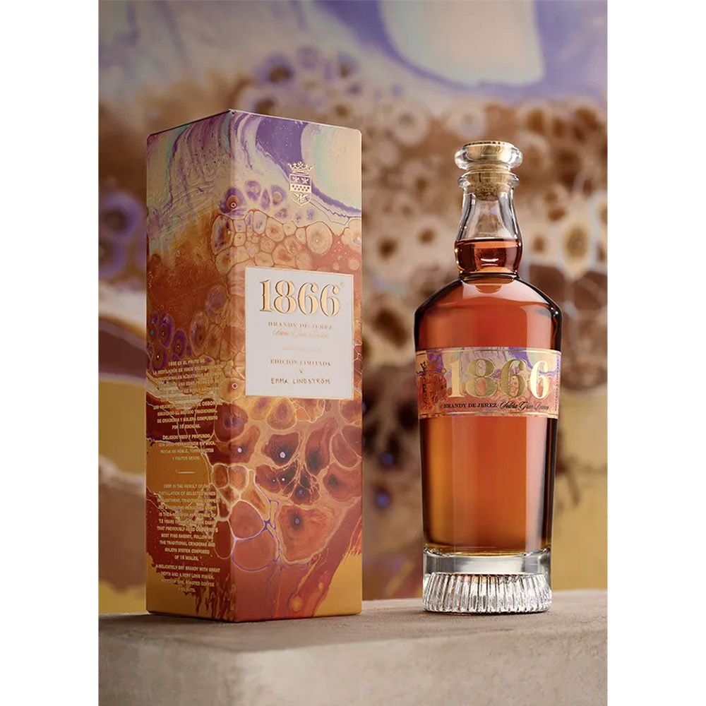 Osborne 1866 Brandy Solera Gran Reserva rappresenta l’eccellenza dell’arte distillatoria spagnola, un capolavoro nato da oltre 150 anni di tradizione e dal leggendario sistema “criaderas y solera” composto da 16 livelli di botti di rovere. Questa edizione limitata, creata in collaborazione con l’artista svedese Emma Lindström, unisce la maestria del blending di brandy e l’energia del colore fluido, celebrando l’armonia tra arte e tempo. Distillato da vini Airén della Mancia nelle tradizionali alquitaras di rame, il Brandy 1866 matura per una media di dodici anni in botti che hanno precedentemente contenuto i migliori sherry di Osborne. Il risultato è un brandy ricco, profondo e vellutato, dal colore mogano intenso con riflessi dorati, capace di conquistare gli appassionati più esigenti. Al naso rivela note di uvetta, vaniglia e caramello, mentre al palato esprime frutta secca, legni nobili e accenti salmastri che ne definiscono la morbidezza e la finezza. Il finale è lungo, caldo e rotondo, con una piacevole dolcezza bilanciata da tocchi secchi e speziati. Ogni bottiglia della Limited Edition 1866 x Emma Lindström è un’opera d’arte: i toni ambra, oro e terra evocano i colori del brandy e del paesaggio andaluso di El Puerto de Santa María, dove nasce e invecchia.Un brandy leggendario, simbolo di passione, equilibrio e tradizione, che racchiude nel suo profumo tutta la storia e l’anima dell’Andalusia.