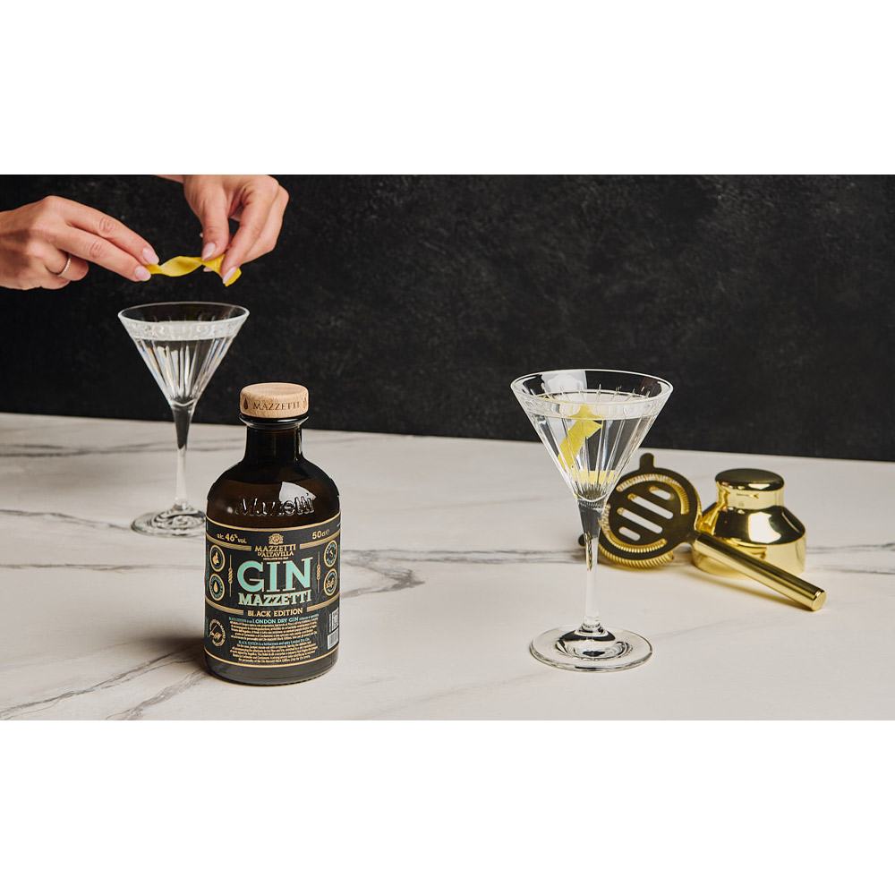 Mazzetti Momento Martini con Gin Black Edition e Accessori - Non è un semplice cocktail: il Martini è un rito. Con Momento Martini, Mazzetti d’Altavilla celebra l’icona della miscelazione internazionale racchiudendo in un’unica confezione tutto il necessario per prepararlo alla perfezione. Protagonista del cofanetto è il Gin Black Edition, elegante e deciso, con note botaniche fini e pulite che si sposano idealmente con il Martini dry. Insieme al gin, la confezione include calici dedicati RCR, shaker e accessori dorati, per trasformare ogni preparazione in un gesto consapevole e raffinato. Un kit completo pensato per chi vuole vivere l’esperienza del Martini nel suo stile originale: dal movimento dello shaker al suo tipico profumo aromatico, fino al primo sorso. Non è solo un cocktail.È un momento da celebrare.
