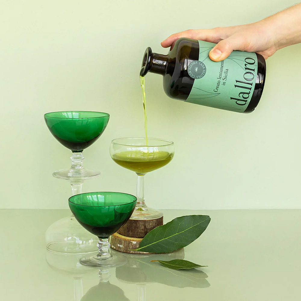Il Liquore all'Alloro "Dalloro" è un inno alla tradizione liquoristica artigianale siciliana. Realizzato a Palermo dalla giovane realtà Casa Allora, questo digestivo d'eccellenza nasce esclusivamente da botaniche coltivate "ad acqua e sole" nella tenuta di famiglia. Lontano dalle logiche e dalle standardizzazioni industriali, "dalloro" è definito dai suoi creatori un vero e proprio "miracolo di lentezza": i tempi di raccolta, essiccazione e infusione seguono rigorosamente i ritmi naturali, senza l'uso di macchinari, additivi chimici o coloranti. Una filosofia etica che abbraccia anche la sostenibilità ambientale, con un processo produttivo a zero sprechi e un packaging completamente riciclabile, per un liquore che esalta il saper fare artigiano e l'amore puro per la terra madre. - Al naso sprigiona i profumi inconfondibili della macchia mediterranea, con intense e avvolgenti note balsamiche tipiche dell'alloro siciliano. In bocca il sorso è fresco, aromatico e ben equilibrato, capace di restituire intatte le rinomate proprietà benefiche e naturali della pianta. Per apprezzarne al meglio la purezza e l'efficacia digestiva, si consiglia di servirlo rigorosamente freddo o con ghiaccio a fine pasto. La sua spiccata versatilità aromatica lo rende inoltre un ingrediente sorprendente nell'arte della mixology, perfetto per dare un twist mediterraneo ai drink classici o come base per cocktail innovativi.