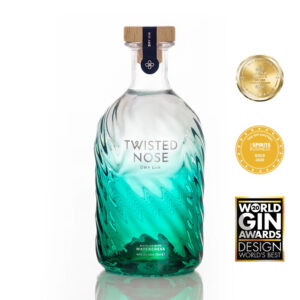 Twisted Nose Gin è un gin secco pluripremiato prodotto nell’Hampshire, pensato per racchiudere la purezza e la freschezza dei corsi d’acqua calcarei (chalk streams) che scorrono vicino alla distilleria. Realizzato in piccoli lotti e distillato lentamente in alambicchi di rame, nasce per valorizzare la provenienza e il legame con un habitat naturale unico. La firma aromatica è il crescione fresco locale, naturalmente pepato, che dà al distillato un tocco stimolante e un finale vivace e persistente; il riferimento storico richiama il nome romano “Nasturtium”, interpretato come “naso storto”. Accanto al ginepro, una selezione di botaniche completa il profilo con equilibrio: pompelmo, corteccia di cassia, semi di finocchio, iris, radice di angelica, lavanda, agrumi e coriandolo, distillate con cura per mantenerne gli aromi freschi e delicati. Al naso risulta morbido, con sfumature erbacee e un accenno speziato; al palato è fresco, secco e ben bilanciato, con note di pompelmo e finocchio, cenni delicatamente floreali e una chiusura pepata distintiva legata al crescione. La persistenza è lunga e pulita, con una sensazione complessiva intensa ma mai pesante. Anche il design è parte dell’esperienza: la bottiglia personalizzata in vetro blu-verde presenta un effetto ondulato che increspa e rifrange la luce come la superficie di un ruscello, anticipando visivamente la sua anima “di fiume”. In servizio è ideale in Gin Tonic con una fetta di pompelmo rosa per esaltare la componente agrumata, ed è eccellente anche in Martini con vermouth, dove la sua secchezza e la traccia erbacea emergono con grande precisione.