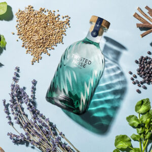 Twisted Nose Gin è un gin secco pluripremiato prodotto nell’Hampshire, pensato per racchiudere la purezza e la freschezza dei corsi d’acqua calcarei (chalk streams) che scorrono vicino alla distilleria. Realizzato in piccoli lotti e distillato lentamente in alambicchi di rame, nasce per valorizzare la provenienza e il legame con un habitat naturale unico. La firma aromatica è il crescione fresco locale, naturalmente pepato, che dà al distillato un tocco stimolante e un finale vivace e persistente; il riferimento storico richiama il nome romano “Nasturtium”, interpretato come “naso storto”. Accanto al ginepro, una selezione di botaniche completa il profilo con equilibrio: pompelmo, corteccia di cassia, semi di finocchio, iris, radice di angelica, lavanda, agrumi e coriandolo, distillate con cura per mantenerne gli aromi freschi e delicati. Al naso risulta morbido, con sfumature erbacee e un accenno speziato; al palato è fresco, secco e ben bilanciato, con note di pompelmo e finocchio, cenni delicatamente floreali e una chiusura pepata distintiva legata al crescione. La persistenza è lunga e pulita, con una sensazione complessiva intensa ma mai pesante. Anche il design è parte dell’esperienza: la bottiglia personalizzata in vetro blu-verde presenta un effetto ondulato che increspa e rifrange la luce come la superficie di un ruscello, anticipando visivamente la sua anima “di fiume”. In servizio è ideale in Gin Tonic con una fetta di pompelmo rosa per esaltare la componente agrumata, ed è eccellente anche in Martini con vermouth, dove la sua secchezza e la traccia erbacea emergono con grande precisione.