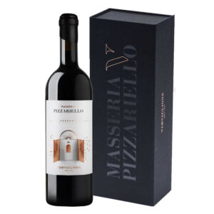 Il Masseria Pizzariello Puglia IGT Rosso di Varvaglione è un vino evocativo e maestoso, creato per celebrare in un calice il primo secolo di storia della cantina pugliese. Nel bicchiere si presenta con un colore rosso intenso e profondo, dai caldi riflessi granata. Al naso è un mosaico complesso e mediterraneo: profumi di amarena e frutta rossa matura si fondono a note suadenti di albicocca secca, frutta a guscio e miele, impreziosite da tocchi speziati di pepe bianco, liquirizia e macchia mediterranea. Al palato l'ingresso è secco e rotondo: un sorso di straordinaria struttura e morbidezza, che avvolge la bocca in una persistenza lunga e appagante. ​- Questo prezioso blend di Primitivo, Negroamaro e Aglianico nasce come "single vineyard" nei vigneti della famiglia Varvaglione, raccolti rigorosamente con una vendemmia notturna per preservarne l'energia aromatica. Il nome è un omaggio alla Masseria Pizzariello, storica dimora del Seicento e vero cuore pulsante della famiglia, dove Cosimo Varvaglione da bambino vinificava le uve con il padre e il nonno. In cantina, la vinificazione prevede tre settimane di macerazione a temperatura controllata, seguite da un affinamento lento e rispettoso di 9 mesi in botti grandi e da un successivo riposo in bottiglia, studiato per armonizzarne la grande complessità.