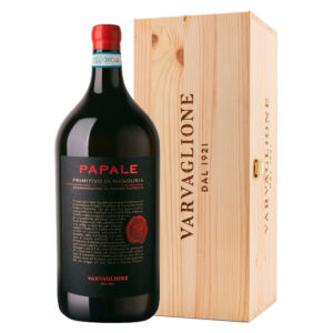 Il Papale Primitivo di Manduria DOP di Varvaglione è un rosso dal fascino mediterraneo, capace di esprimere nel calice tutta l'intensità e il calore del sole pugliese. Si presenta alla vista con un colore rosso carico, profondo, acceso da luminosi e intensi riflessi violacei. Al naso sprigiona un bouquet ricco e avvolgente: decisi sentori di frutti di bosco in confettura — mora, ciliegia, ribes nero e lampone — si intrecciano a morbide ed eleganti note di vaniglia, cioccolato e liquirizia sul finale. Al palato l'impatto è energico ma setoso: un sorso caratterizzato da grande morbidezza, rotondità e calore, ben supportato da un tannino maturo che guida verso una chiusura straordinariamente persistente. ​- Il Primitivo è il vitigno simbolo della zona tarantina, e in particolare a Manduria trova da oltre un secolo il suo habitat d'elezione, grazie a un clima caldo e asciutto che ne favorisce la perfetta maturazione. La storica cantina Varvaglione seleziona le uve in purezza per dare vita a questo rosso identitario. Dopo la vendemmia, la vinificazione avviene in serbatoi di acciaio a temperatura controllata con macerazione sulle bucce. Conclusa la fermentazione malolattica, che ne ingentilisce il profilo, il vino riposa in tonneau di rovere francese per almeno 8 mesi, un affinamento studiato per donargli quella struttura e quella complessità aromatica che lo rendono inconfondibile. - Formato Jeroboam da 3 litri con cassetta originale in legno, ideale per serate in compagnia o come confezione regalo.